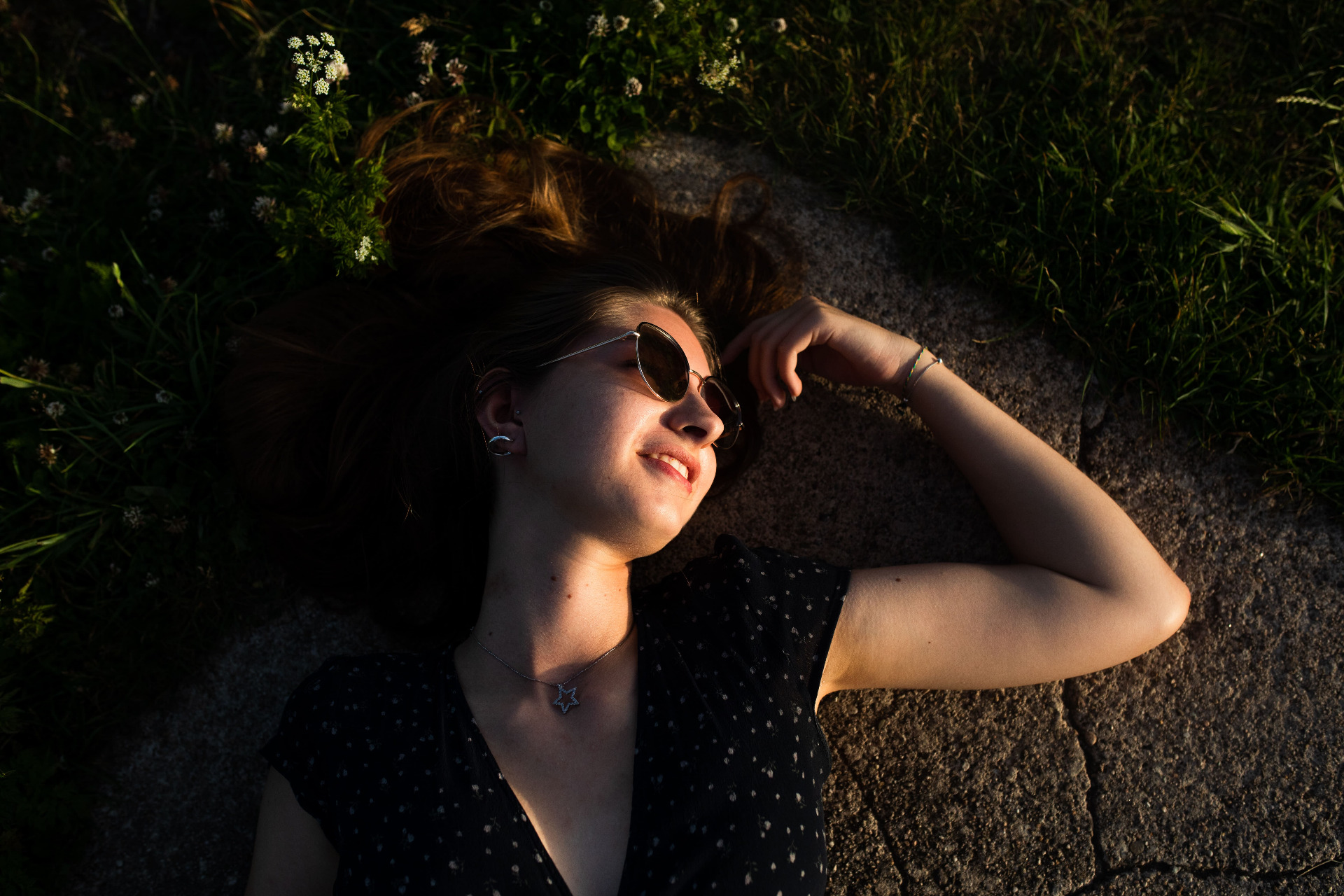 Model posing with sunglasses lying in a field