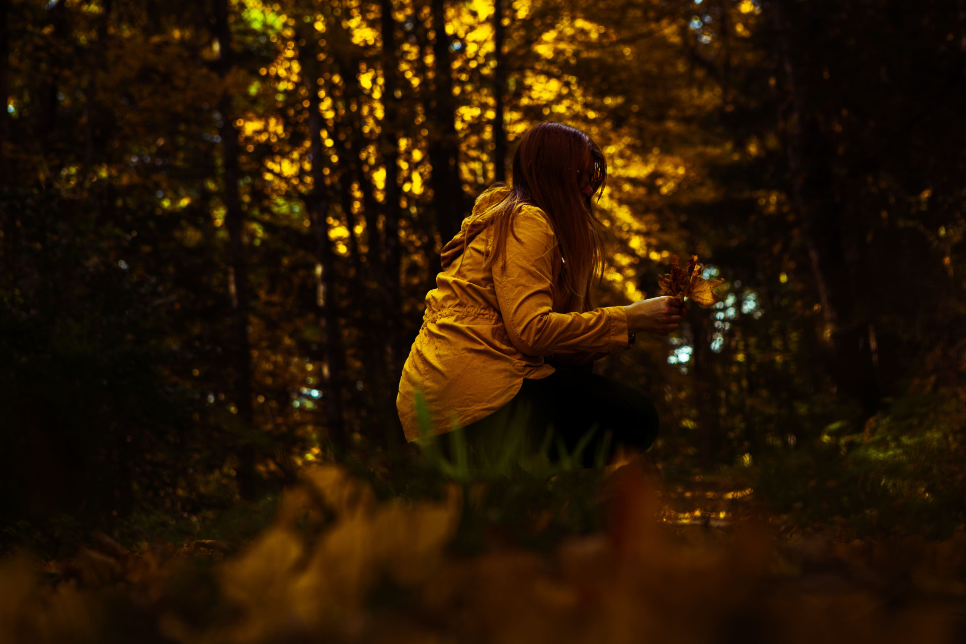 yellow dressed girl kneeling in autum forest