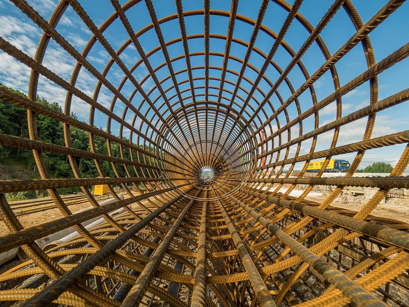 Ironworker tying a reinforcing-bar column cage on a construction site