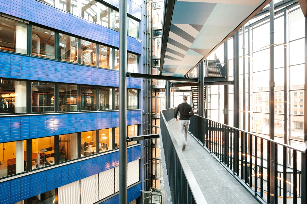 Moderne Bürowelten bei WeWork Hamburg – Flexibles Arbeiten in inspirierender Architektur Glasüberdachter Bürokomplex von WeWork Hamburg mit offener Galerie, modernen Arbeitsplätzen und lichtdurchflutetem Atrium – Sinnbild für neue Arbeitswelten.