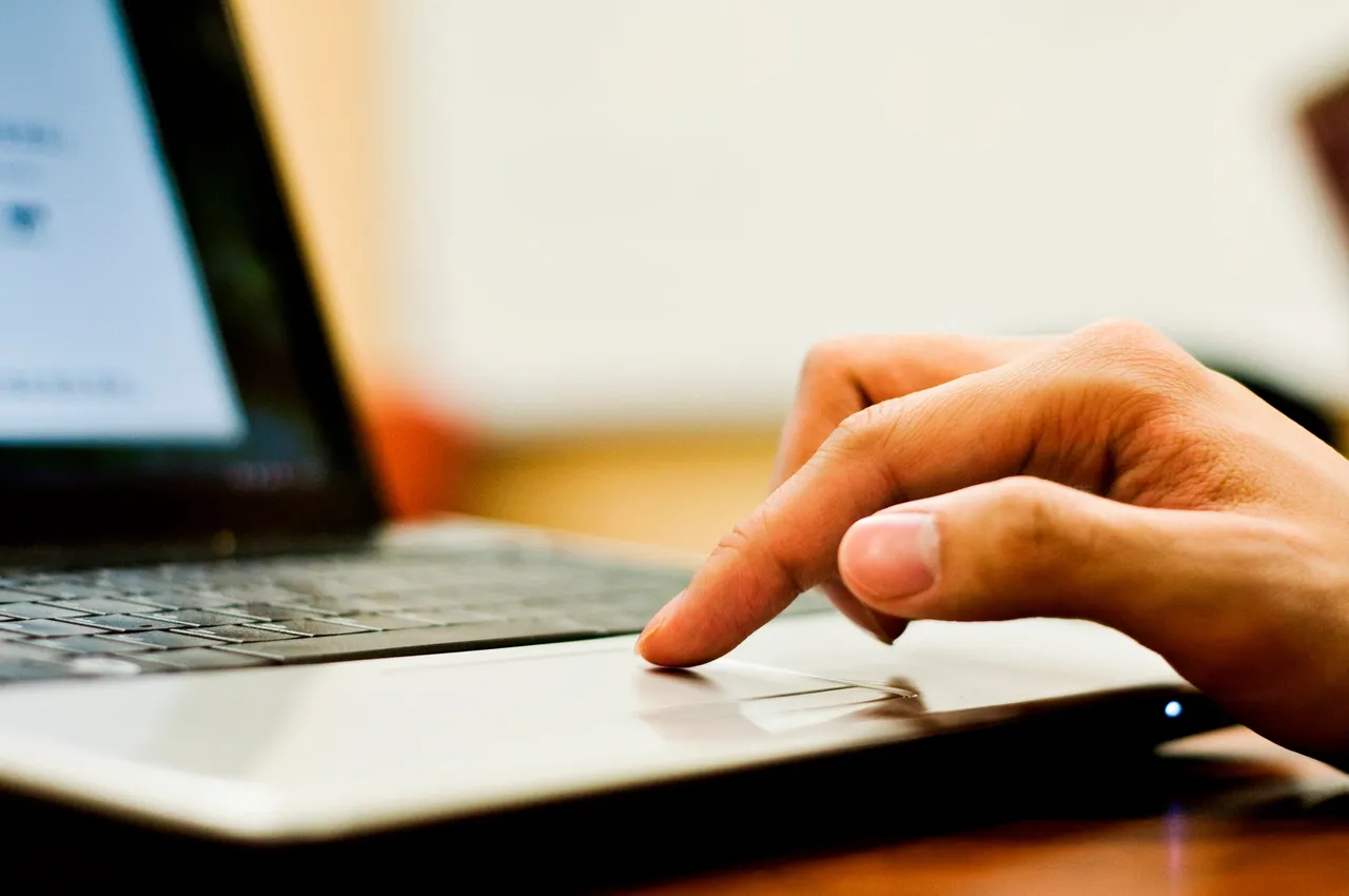 Picture of a person&apos;s hand touching a working laptop