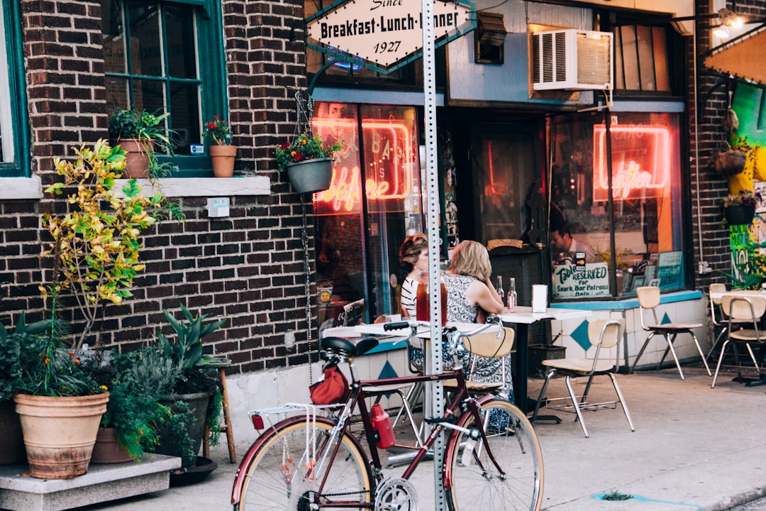 Café store front wih customers outside at a table. A red bike is in the forground.