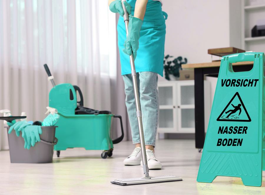 Reinigungskraft mit Warnschild bei der Bodenreinigung