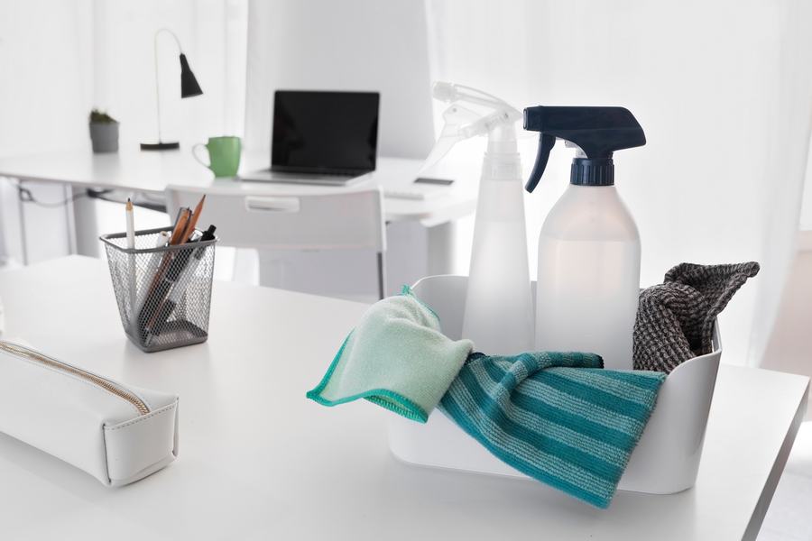 Unterhaltsreinigung im Büro: Reinigungsmittel und Tücher auf dem Schreibtisch