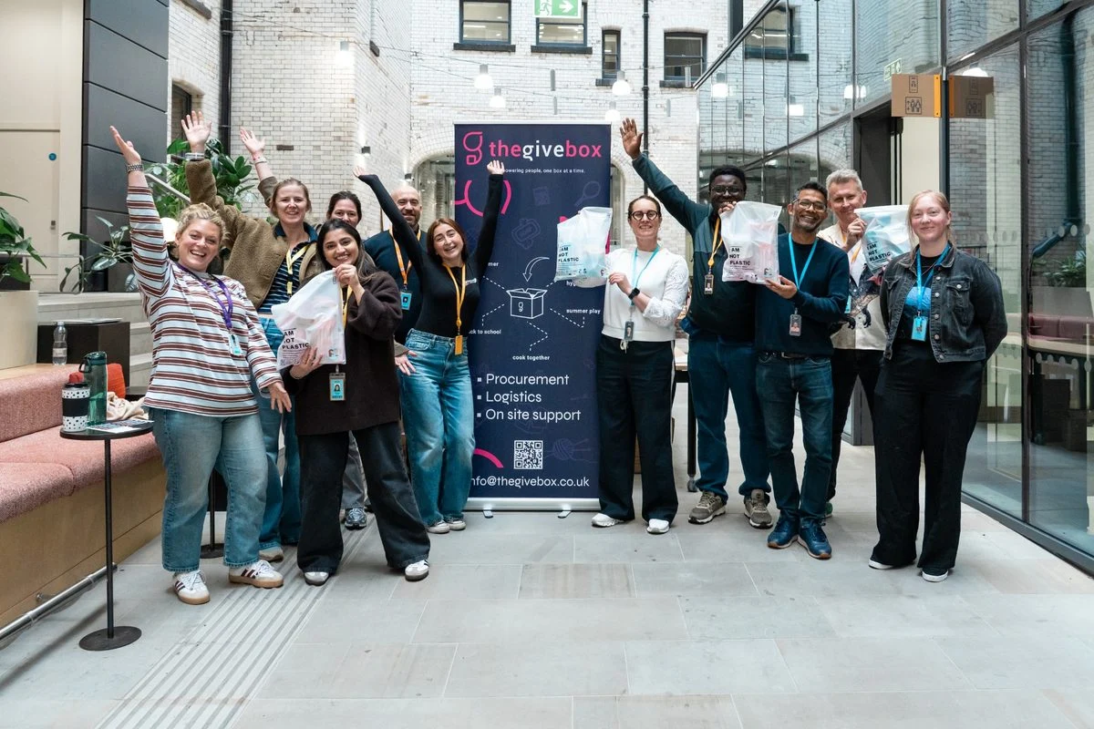 A smiling group of volunteers celebrating together with their packed donation kits