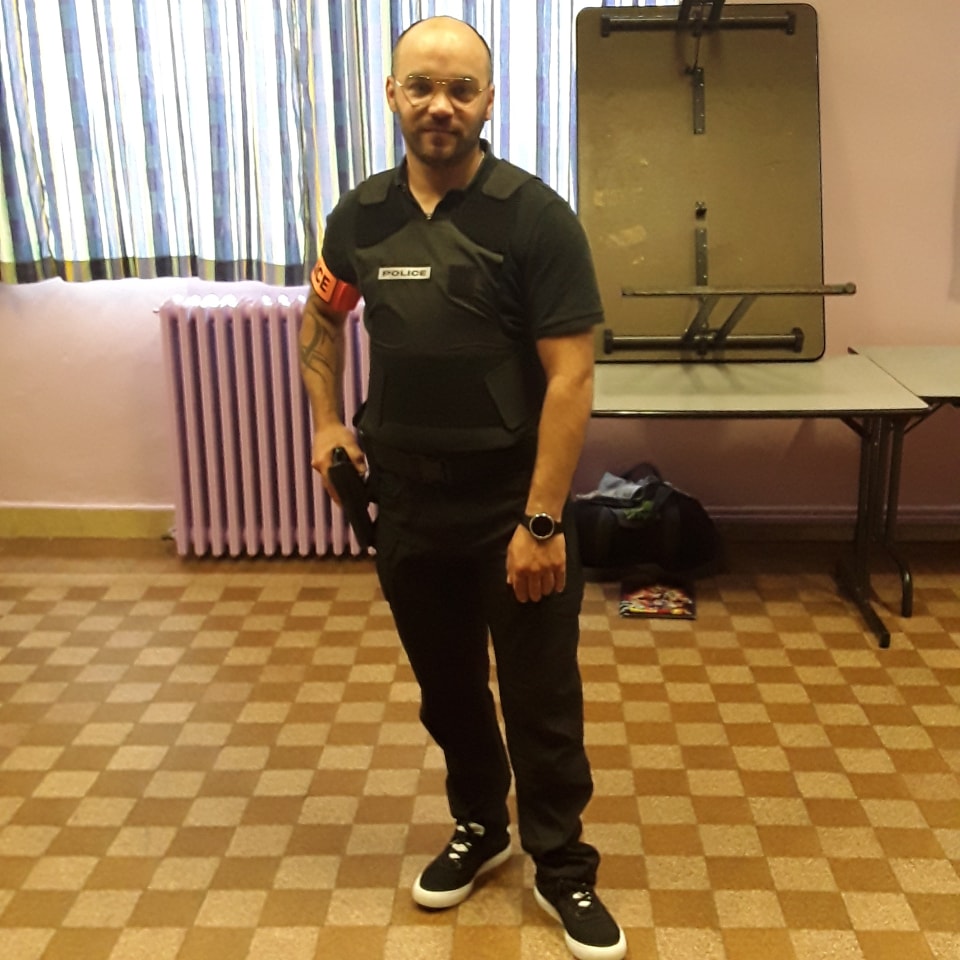 Sébastien Favette, comédien en uniforme de police avec gilet pare-balles, acteur pour séries policières françaises et rôles d'action.