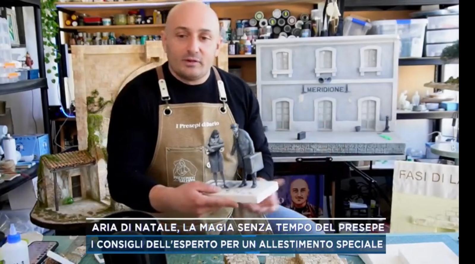 Scenografie e personaggi di presepe esposti sul tavolo di uno studio televisivo