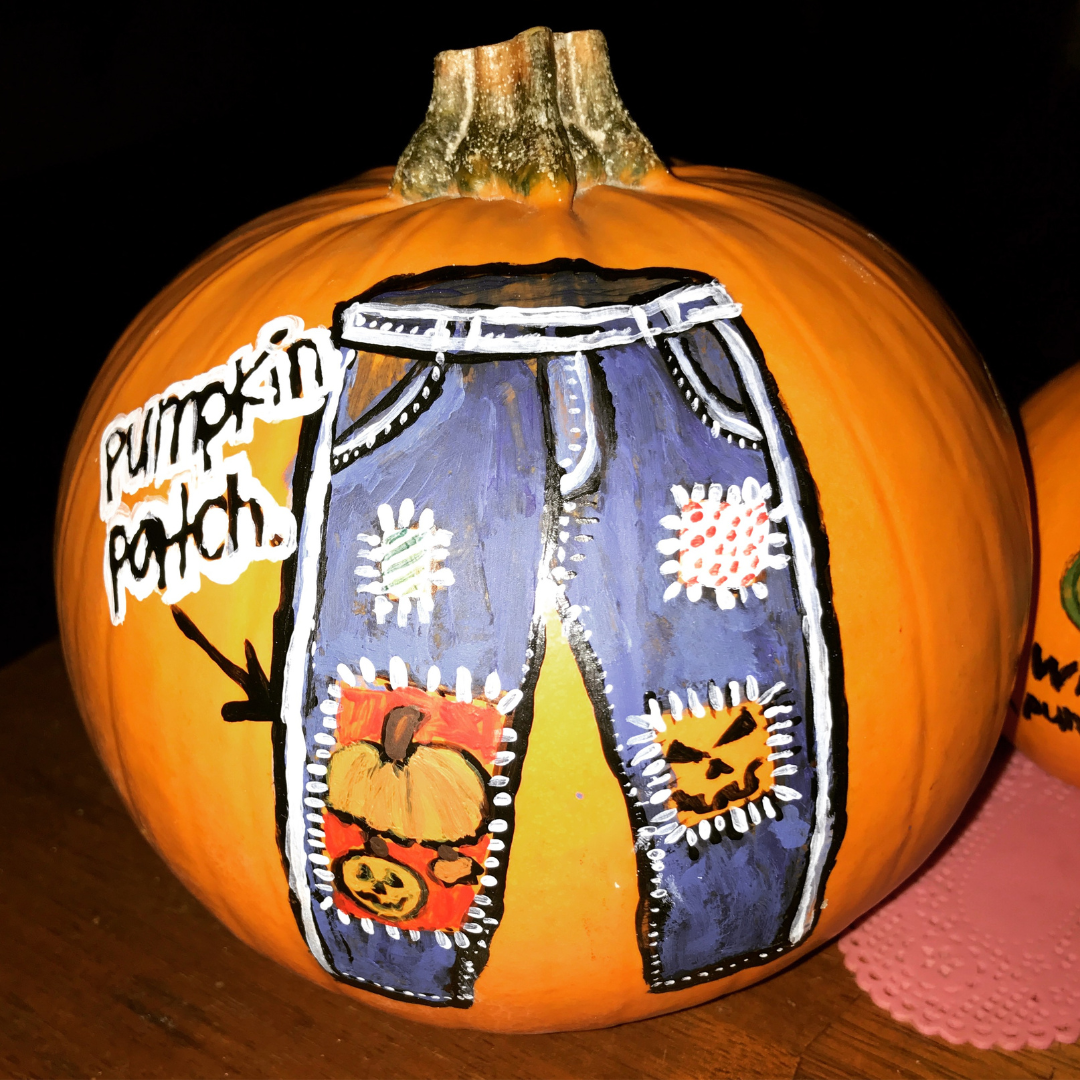 A painted pumpkin sporting a pair of blue jeans with cute pumpkin patches sewn on.